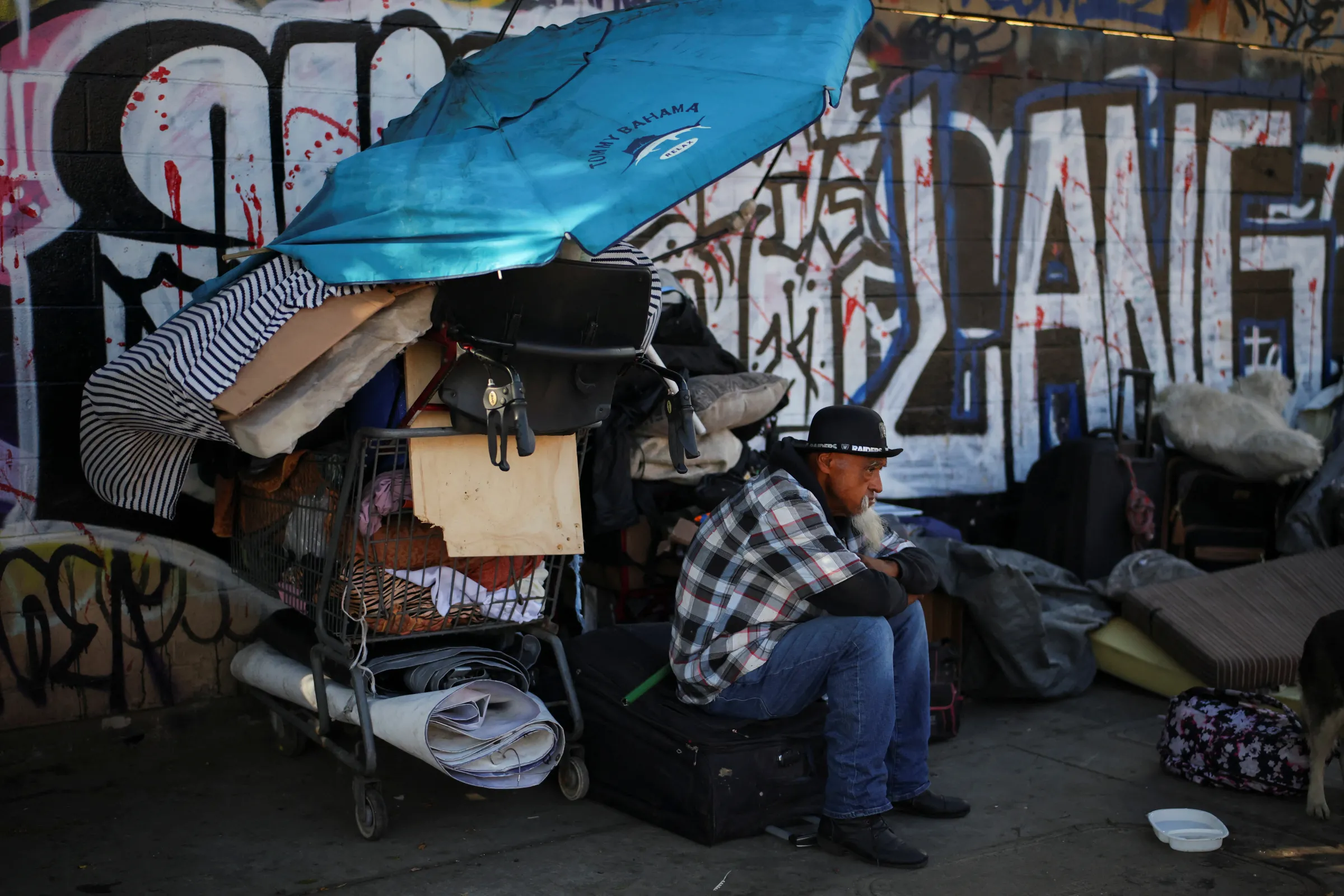 A man sits on a street in Skid Row, Los Angeles, California, U.S., December 9, 2024. REUTERS/Daniel Cole